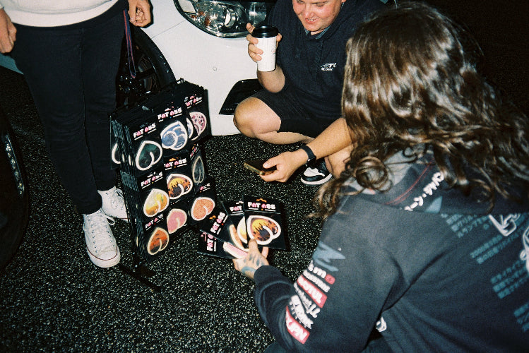Fat ass air fresheners in a carpark with two 3 people