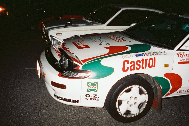 A line of cars taken with flash photography at a fat ass car meet. The car closest to the camera is castrol branded